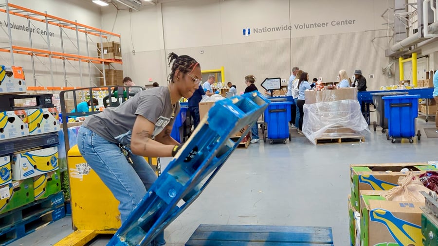 Food bank worker lifting a pallet monitored by safety wearable device
