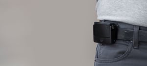 Injury Prevention Technology: A male worker is lifting a box with a wearable device on his belt