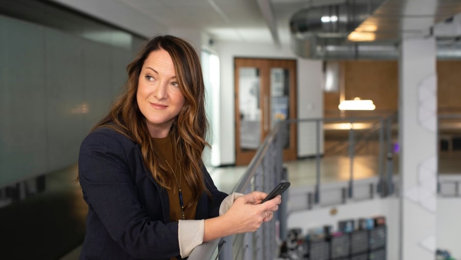 A workers' compensation brokers with a phone in her hand considering the value of AI